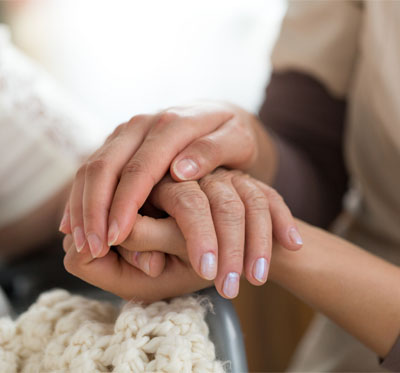 A young woman holds an older woman's hands