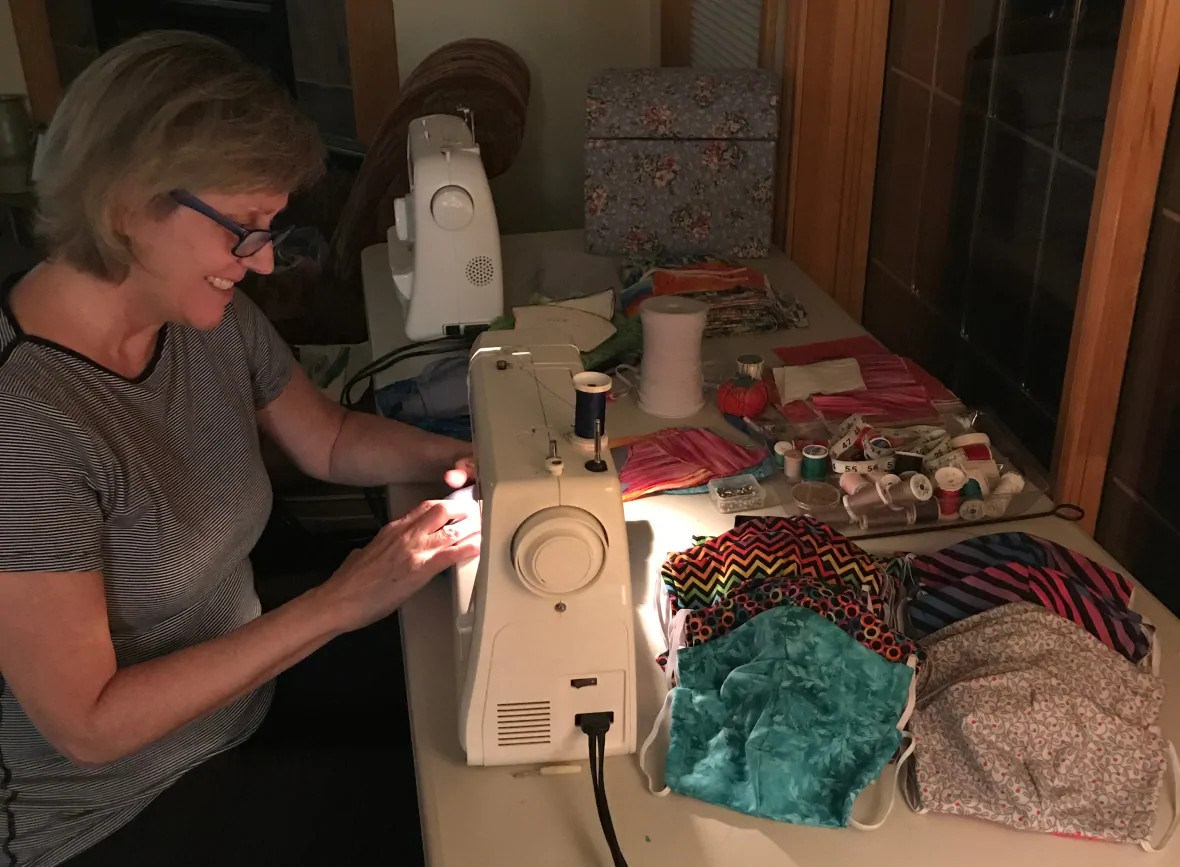 Leslie Byrne at her sewing machine with masks in front of her