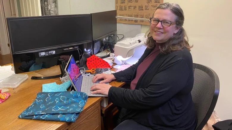 Rebecca Rudman at her laptop with a sewing machine nearby