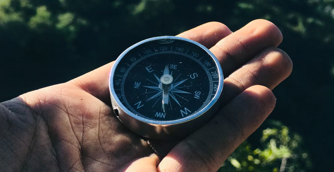 A man's hand holds a compass